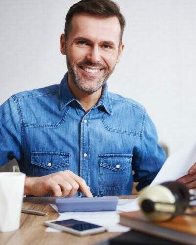 Portrait of smiling man calculating his monthly expenses